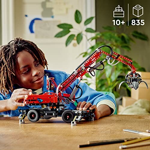 Child playing with LEGO crane set on a table.