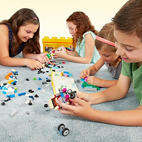 Children playing with colorful LEGO blocks on a carpet.