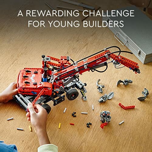 Child assembling a red LEGO crane model with loose pieces on table.